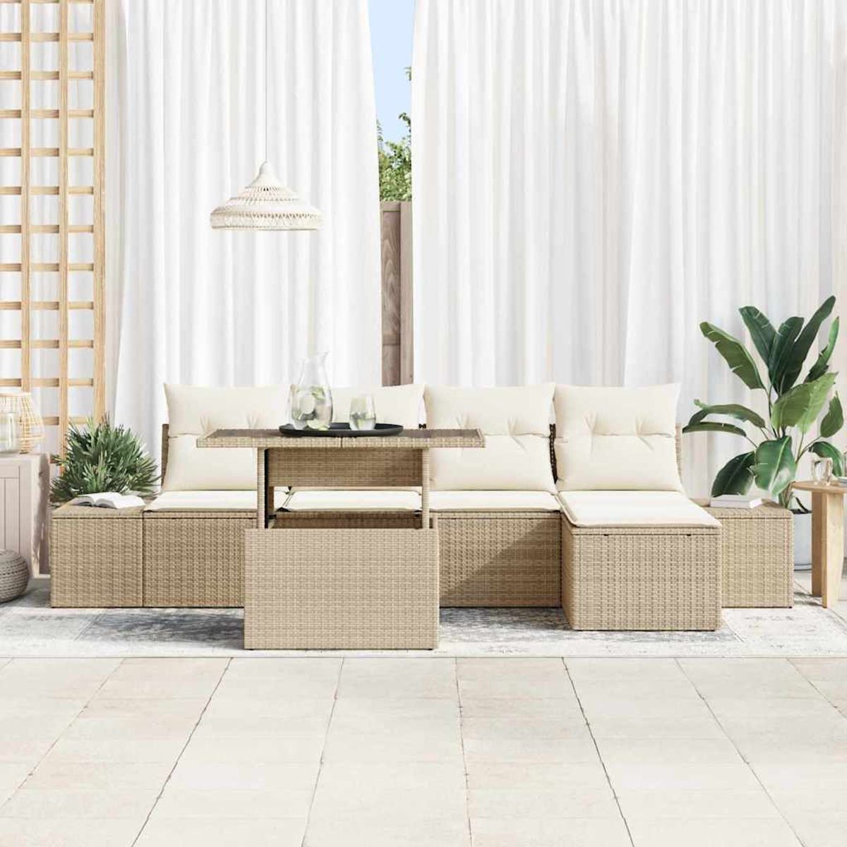Terrassenset mit beigen Korbmöbeln, weißen Kissen und einem Tisch. Weiße Vorhänge im Hintergrund und eine Pflanze rechts.
