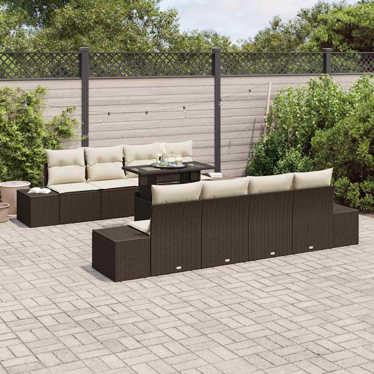 Garten-Terrassenset mit braunen Korbmöbeln, cremefarbenen Kissen und einem kleinen Tisch auf einer grauen Backstein-Terrasse. Im Hintergrund ein Zaun.