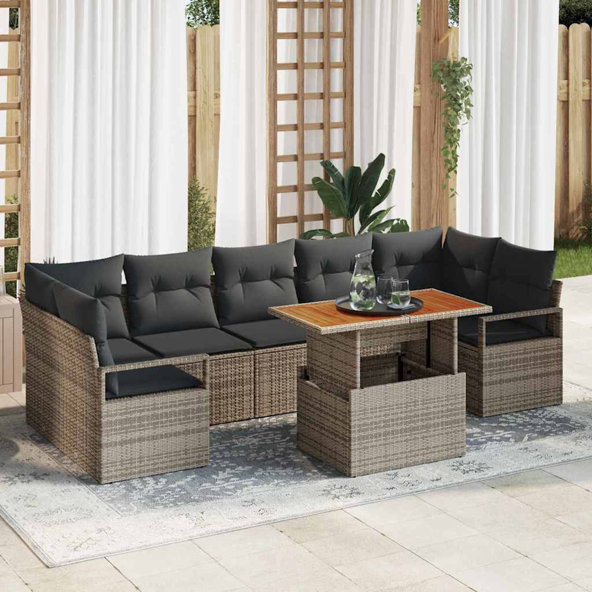 Gartenmöbel-Set mit grauen Kissen, Holztisch und Wasserkrug. Vorhänge und ein Gitter im Hintergrund.