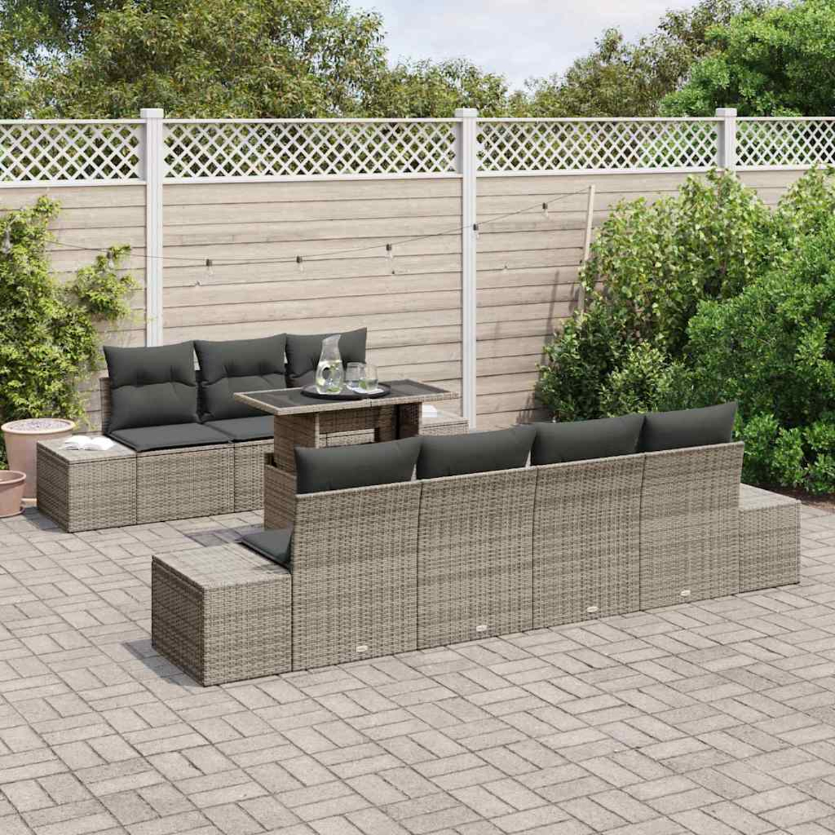 Terrassenset mit grauen Kissen und kleinem Tisch. Szene umfasst Holzzaun und Grün.