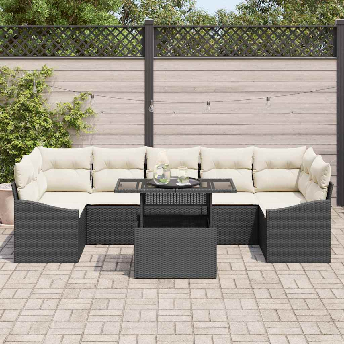 Outdoor-Ecksofa mit cremefarbenen Kissen und einem Tisch mit Glasplatte. Im Hintergrund ein Holzzaun und Grün.