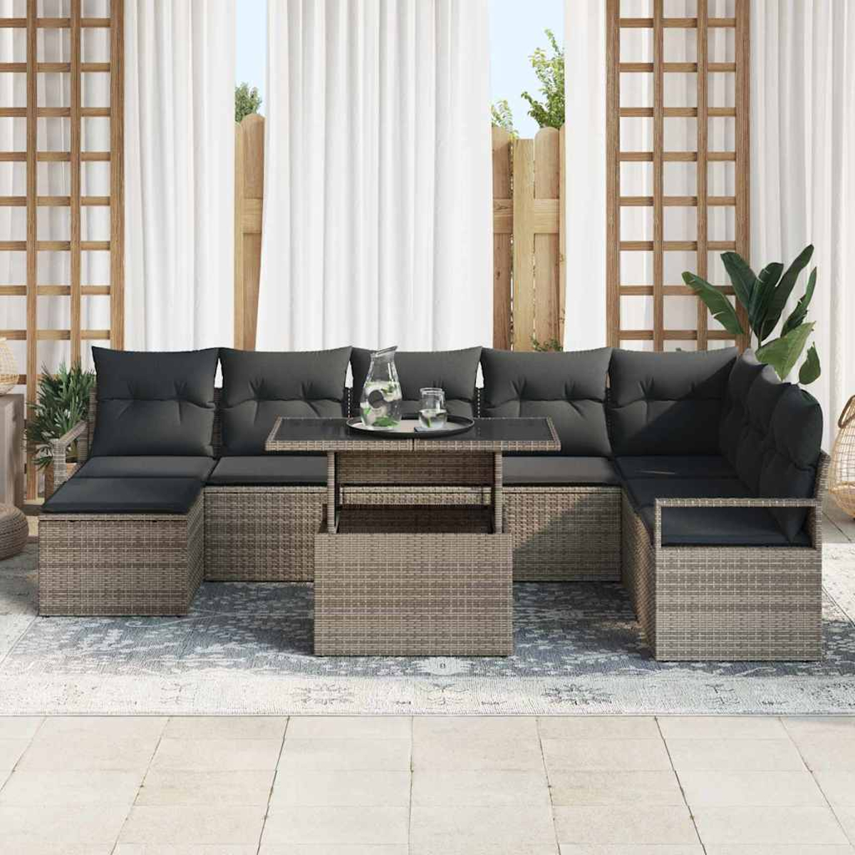 Gartenmöbel-Set mit grauen Kissen und einem Tisch. Weiße Vorhänge und ein Holzgitter im Hintergrund.