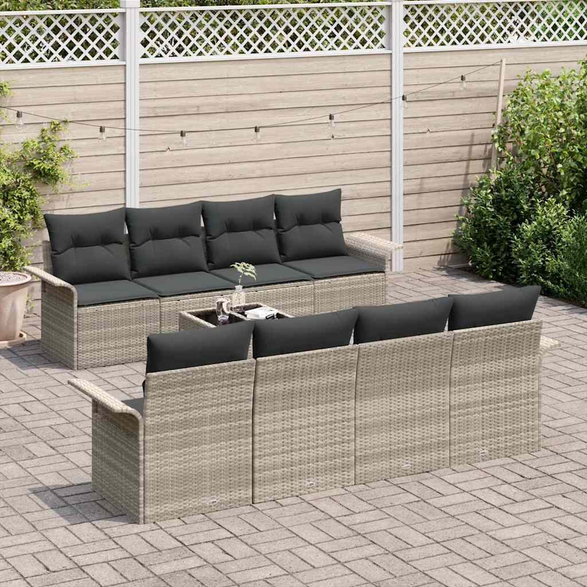 Gartenmöbel-Set mit grauen Kissen auf einer Terrasse. Enthält ein Sofa und zwei Stühle mit einem kleinen Tisch vor einem Zaun.