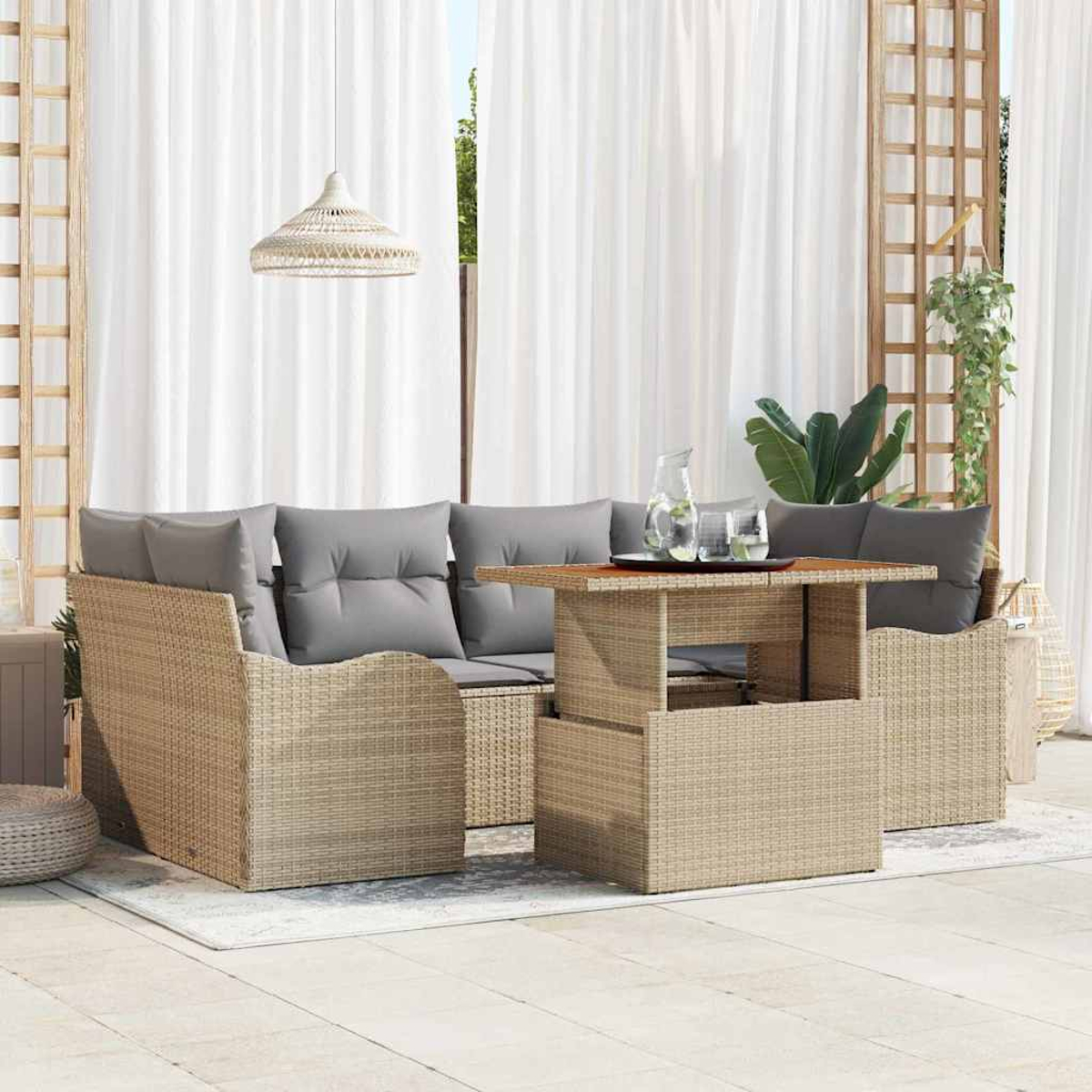 Geflochtenes Outdoor-Möbelset mit Sofa und Tisch. Graue Kissen und weiße Vorhänge im Hintergrund. Glaswaren auf dem Tisch.