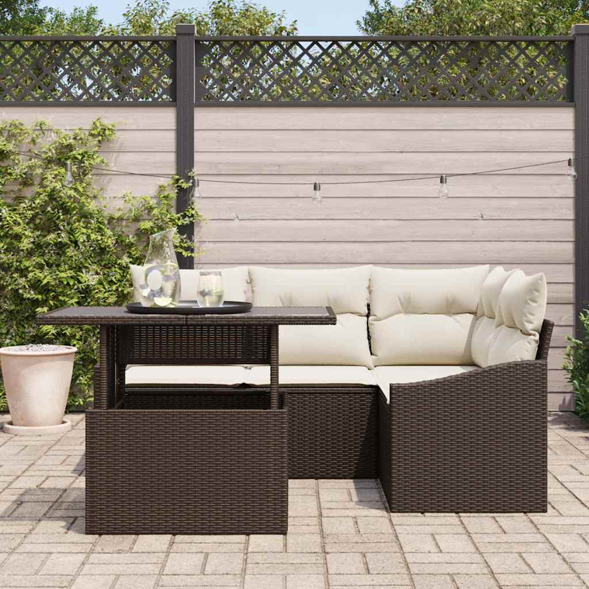 Terrassenset mit braunem Korbmöbel und Tisch. Auf dem Tisch stehen ein Glaskrug und Gläser. Im Hintergrund ein Zaun und Grün.