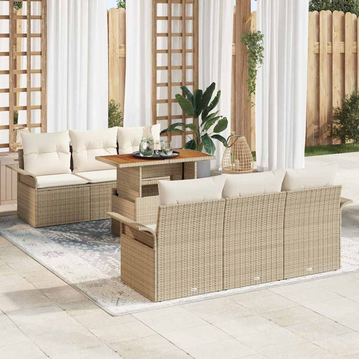 Gartenmöbel-Set mit beigefarbenen Korbsesseln, Tisch und Kissen. Weiße Vorhänge und Holzzaun im Hintergrund.