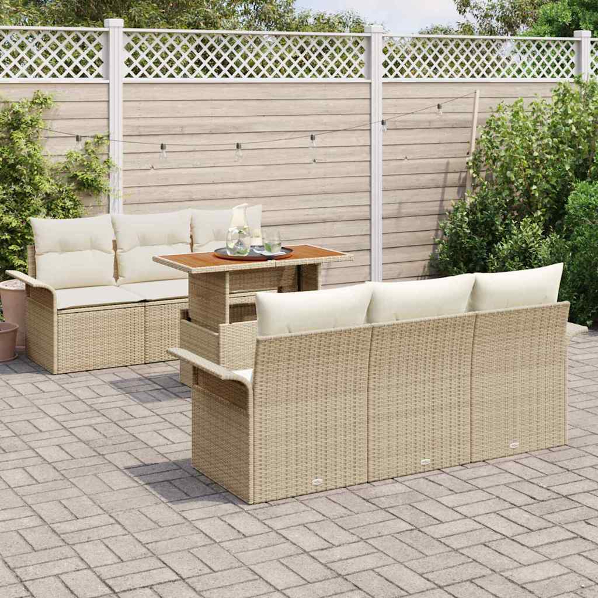 Outdoor-Terrassenset mit beigen Korbmöbeln, cremefarbenen Kissen und einem kleinen Tisch. Im Hintergrund ein Zaun und Grün.