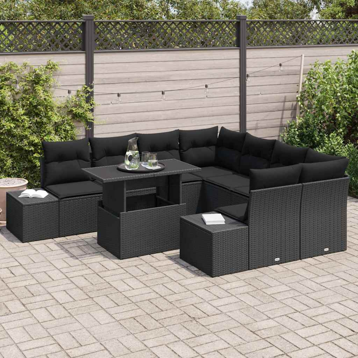 Schwarzes Outdoor-Geflechtsofa-Set mit Kissen, kleiner Tisch mit Gläsern und Krug, auf einer Terrasse. Zaun im Hintergrund.