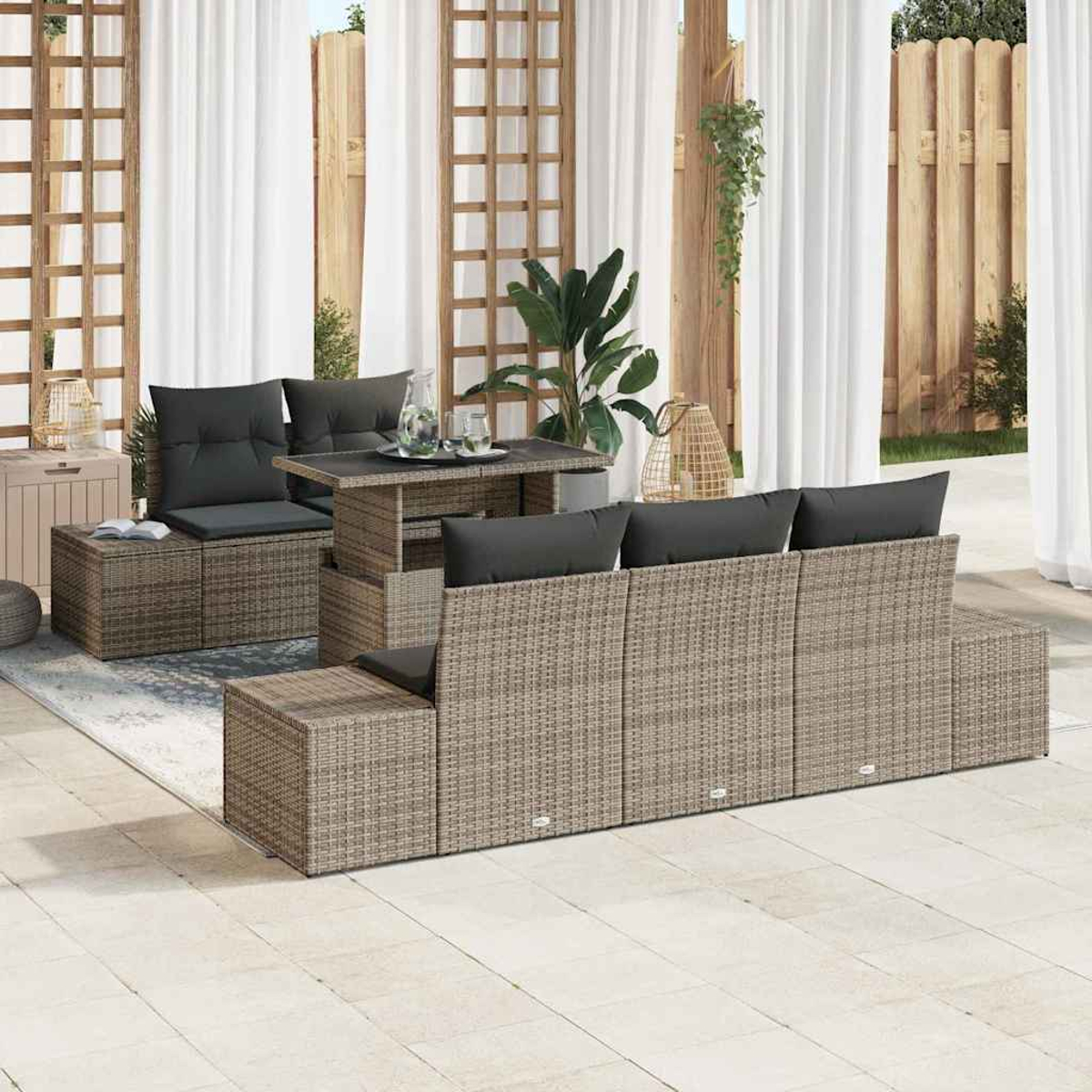 Gartenmöbel-Set mit grauen Kissen und einem Tisch. Weiße Vorhänge und Holzgitter im Hintergrund. Pflanzen und Dekoration sichtbar.