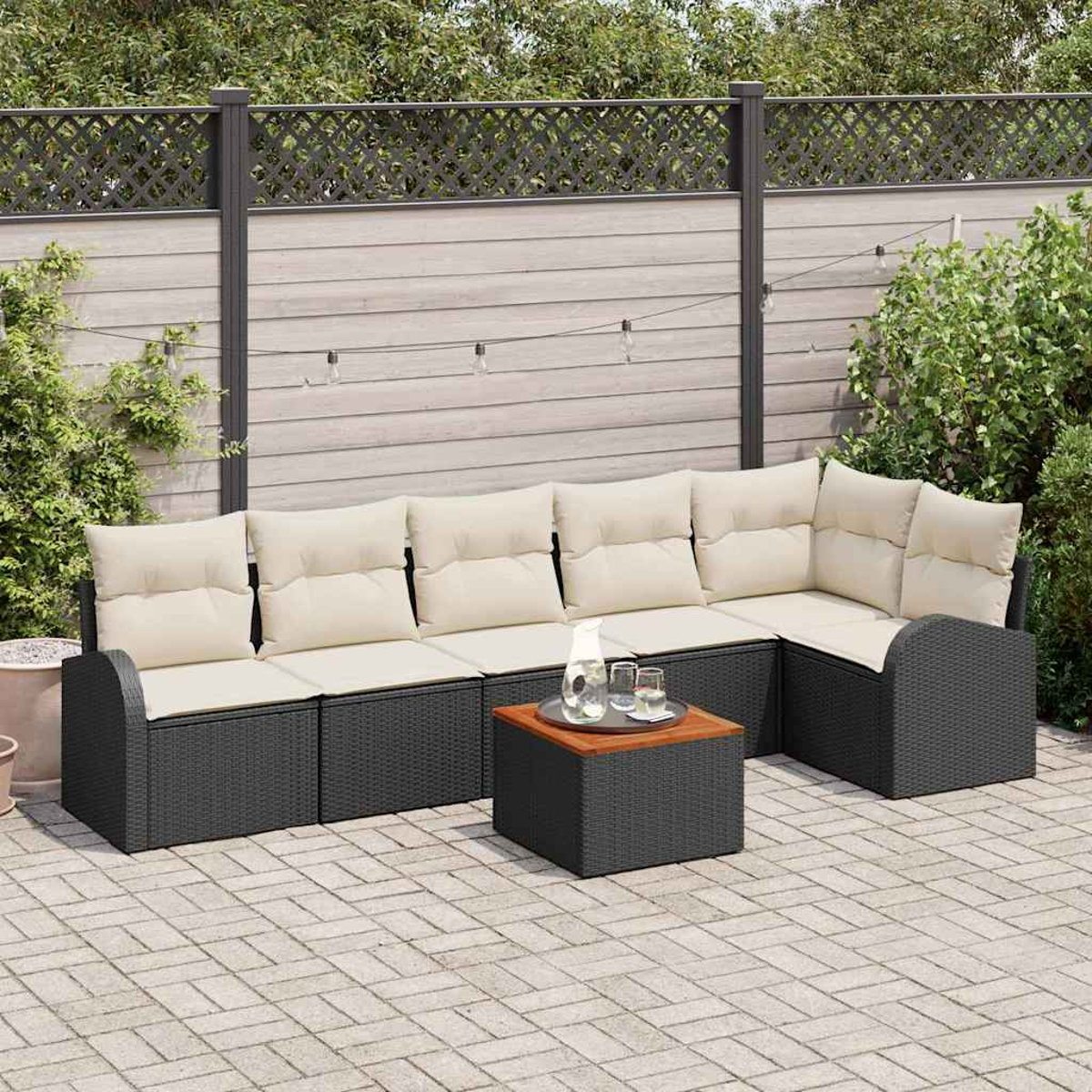 Sofá seccional exterior con cojines crema, base de mimbre negra y mesa de centro de madera. La escena incluye una valla y plantas.
