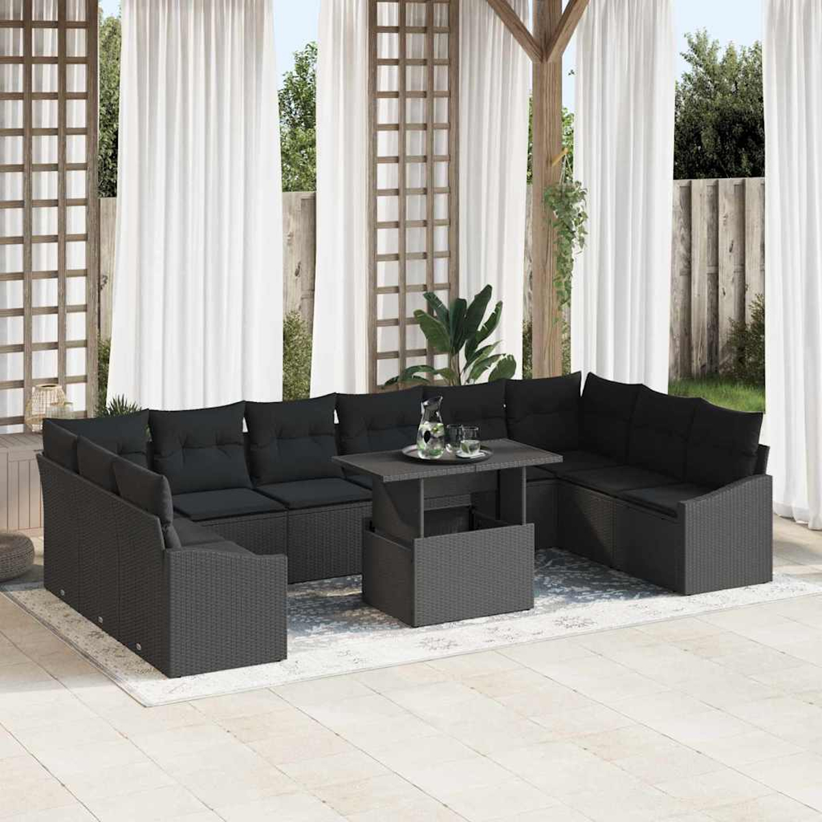 Schwarzes Outdoor-Sofa-Set aus Korbgeflecht mit Kissen und einem Tisch. Weiße Vorhänge und Holzstruktur im Hintergrund.