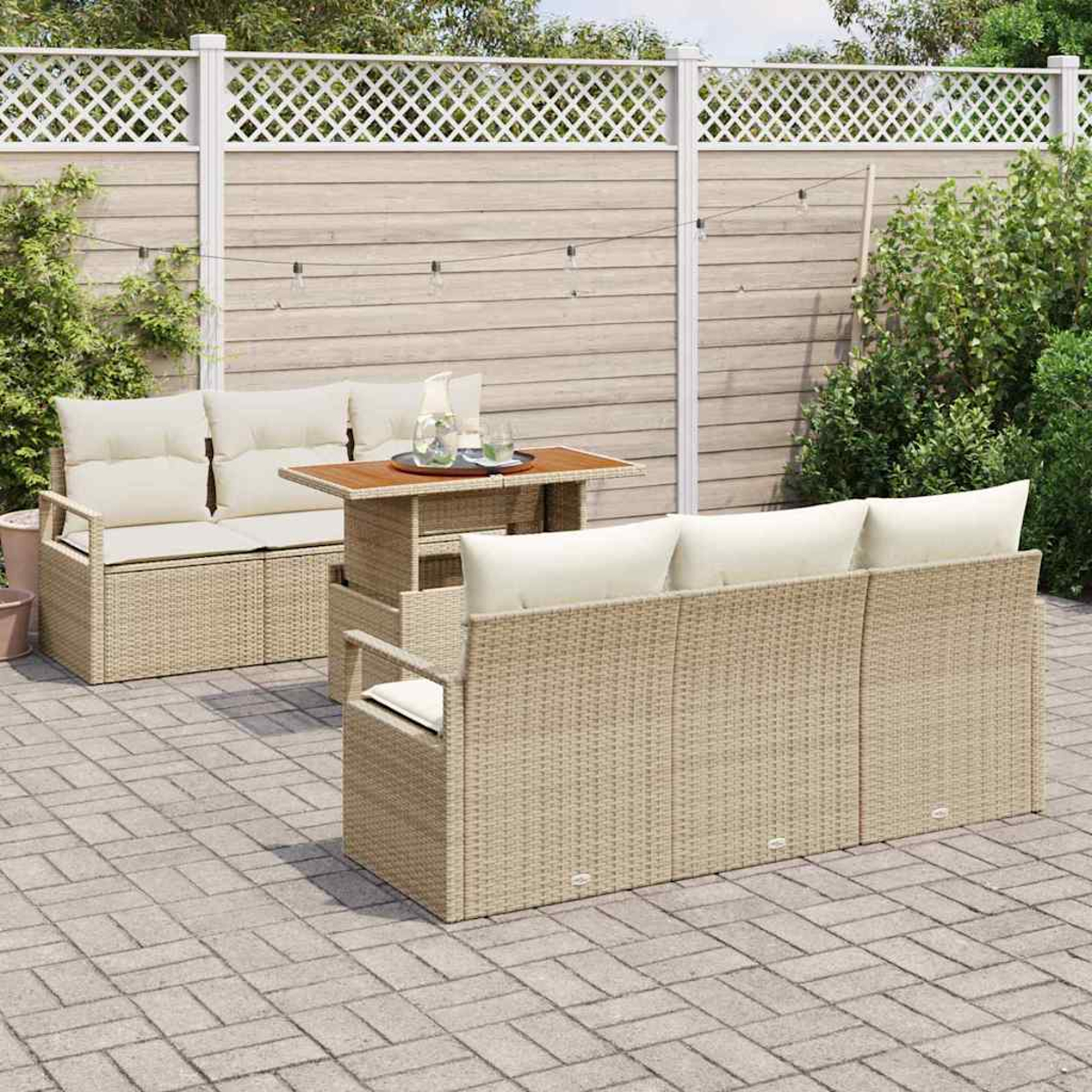 Gartenmöbel-Set mit beigefarbenen Korbsesseln, Kissen und einem Tisch. Im Hintergrund ein Holzzaun, Pflanzen und eine Ziegelterrasse.