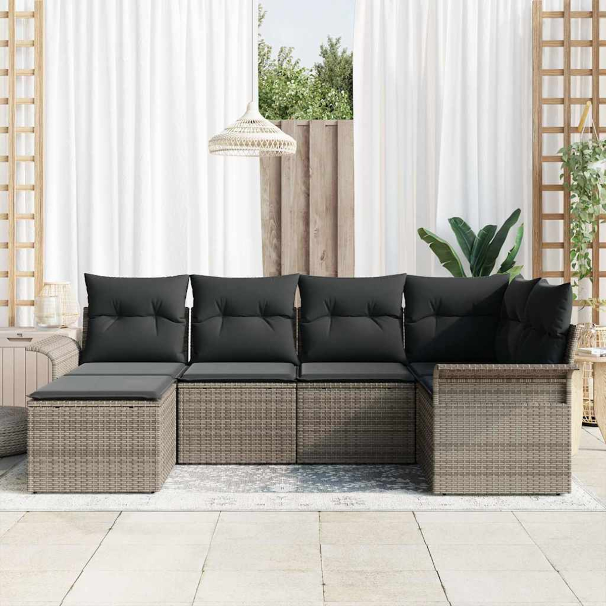 Outdoor-Ecksofa mit grauen Kissen. Dahinter befinden sich weiße Vorhänge, ein Fenster mit Grün und eine Hängelampe.