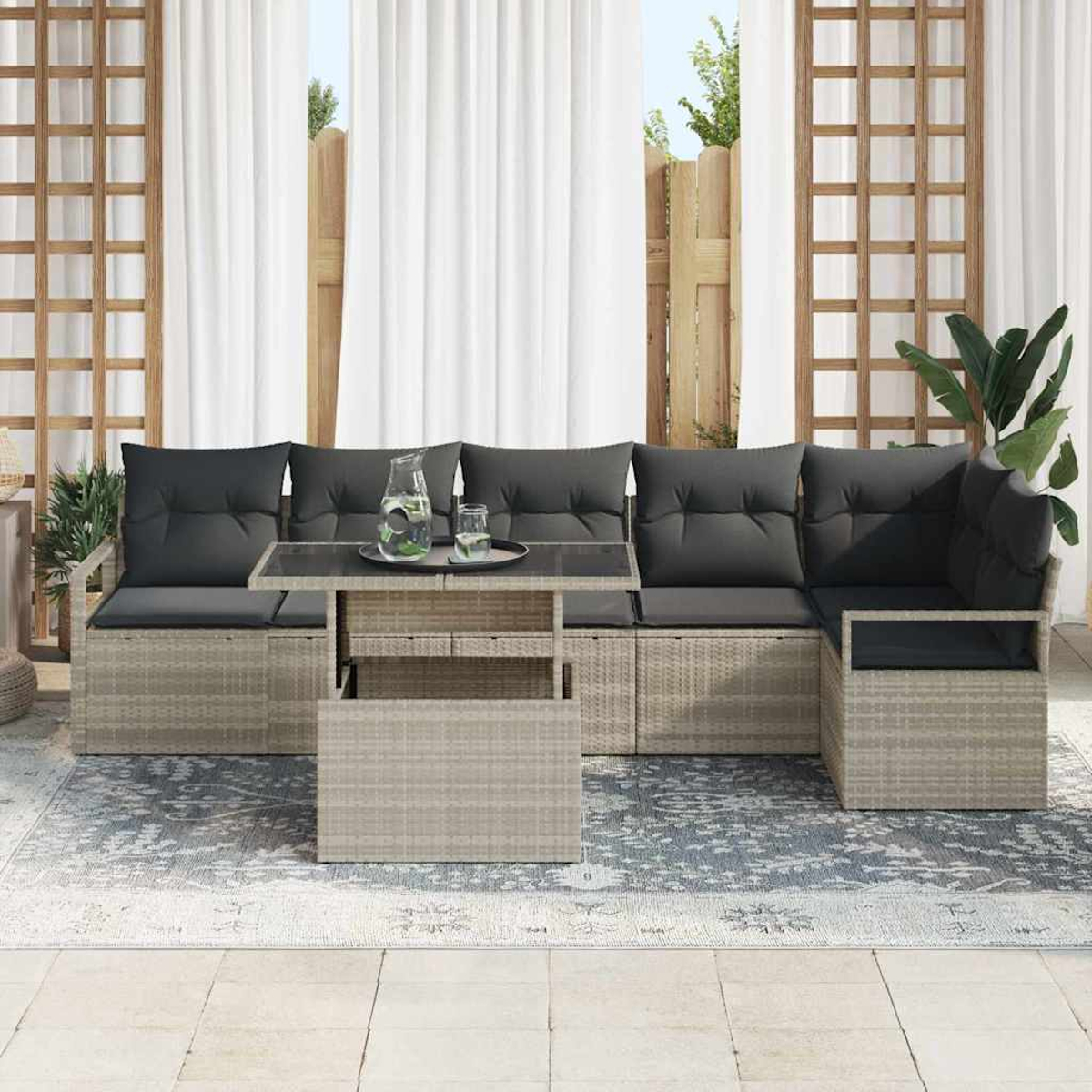 Outdoor-Ecksofa mit grauen Kissen, Glastisch mit Getränken, auf einem Teppich, weiße Vorhänge im Hintergrund.