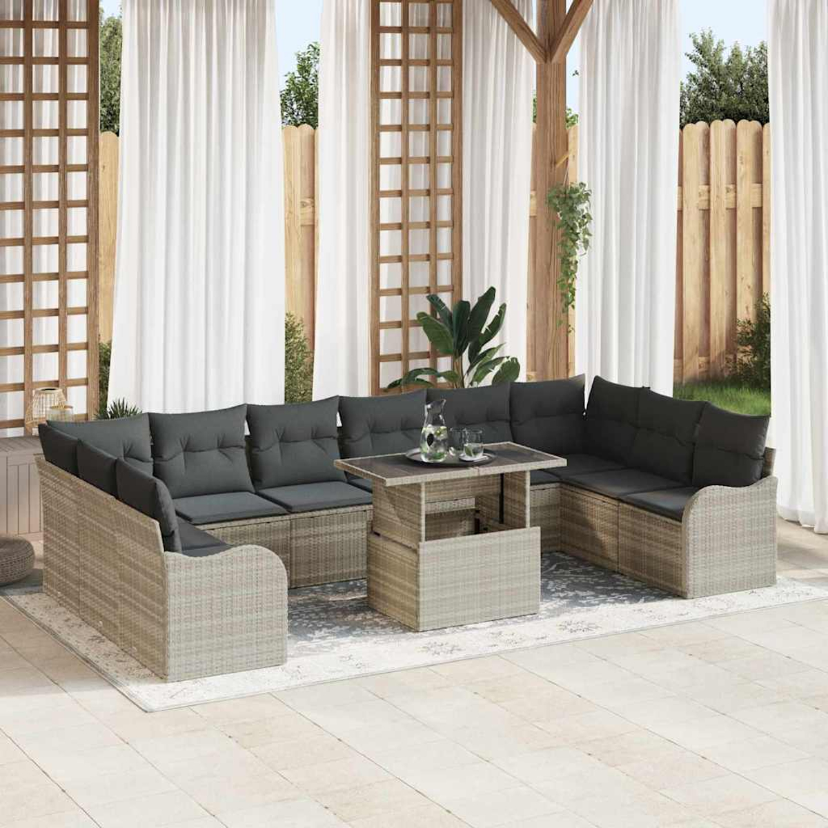 Gartenmöbelset aus Korbgeflecht mit grauen Kissen und einem Tisch. Weiße Vorhänge und Holzgitter im Hintergrund.