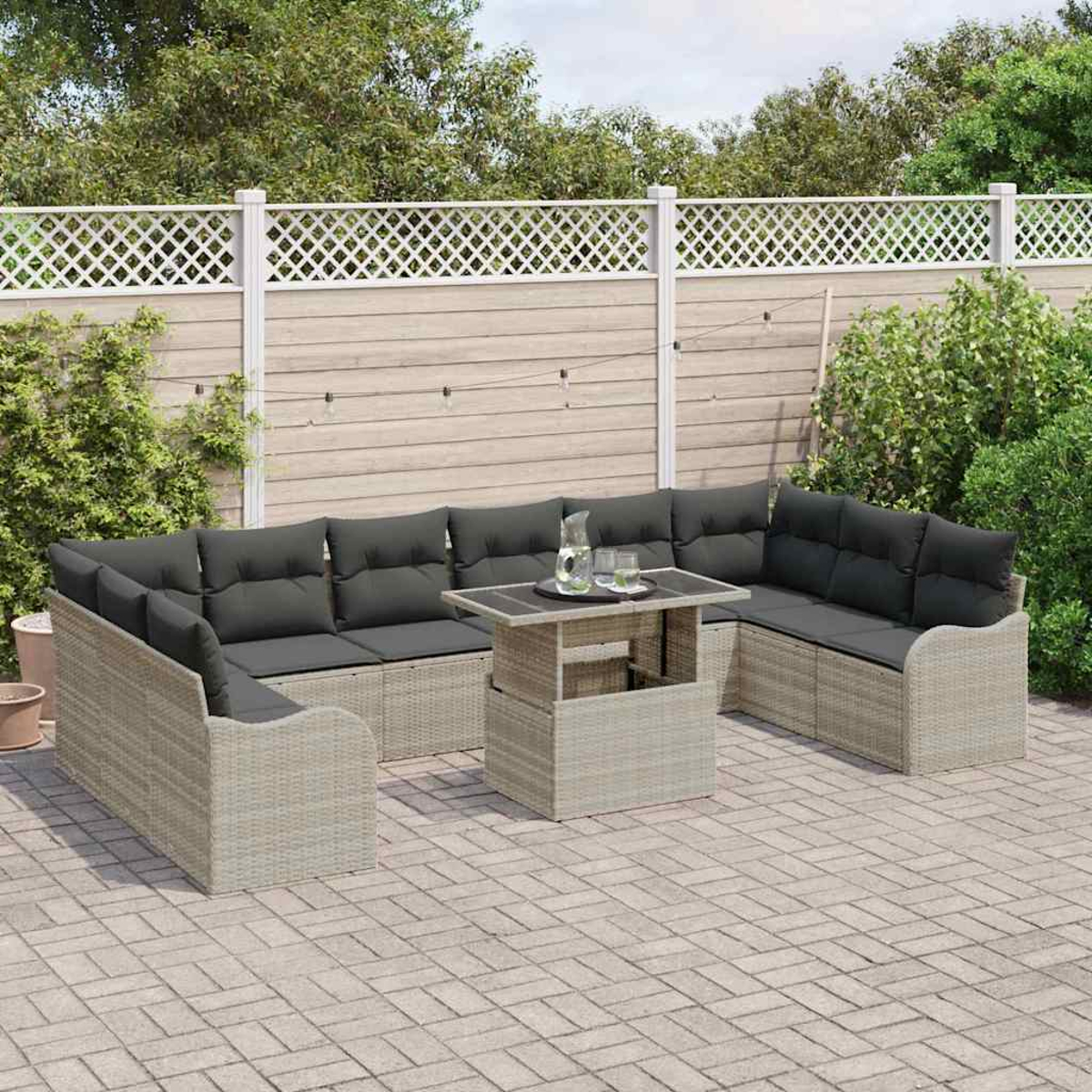Garten-Terrassengarnitur mit grauen Kissen und einem Tisch auf einer gepflasterten Terrasse. Ein weißer Zaun und Grün im Hintergrund.