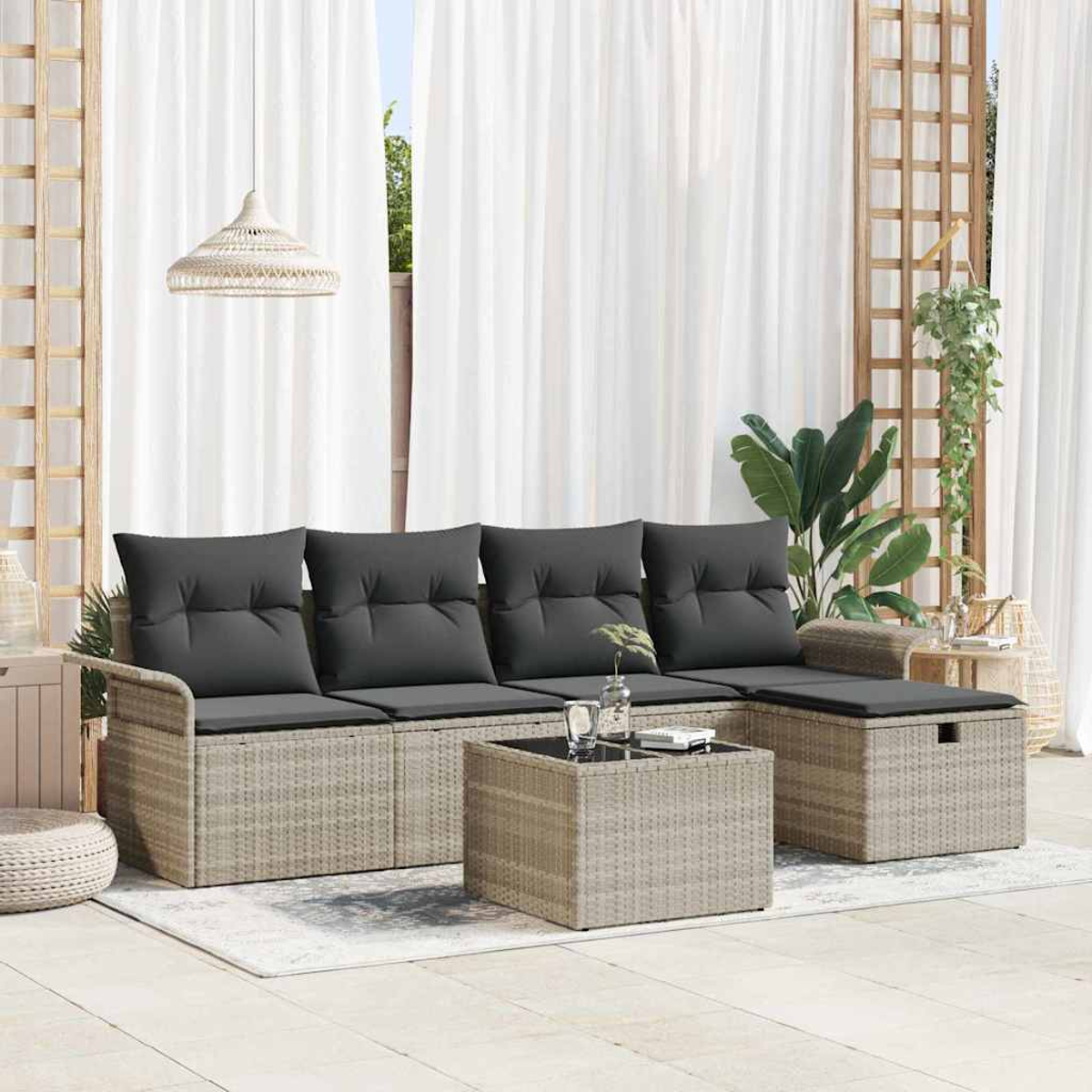 Outdoor-Set mit Korbsessel, Kissen, Couchtisch und Ottoman. Der Hintergrund umfasst weiße Vorhänge, ein Gitter und Pflanzen.