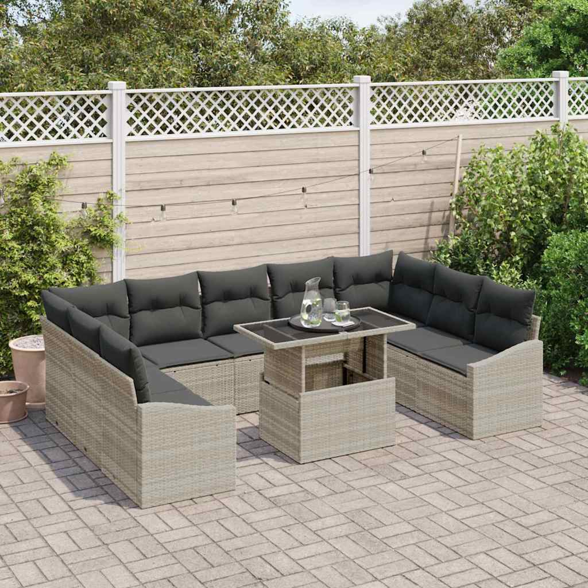Outdoor-Ecksofa-Set mit grauen Kissen und einem Tisch. Es steht auf einer Ziegelterrasse, im Hintergrund ein Zaun und Grün.