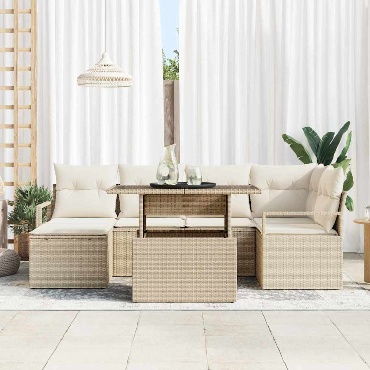 Gartenmöbel-Set aus Korbgeflecht mit cremefarbenen Kissen, einem Tisch mit Getränken und weißen Vorhängen im Hintergrund.