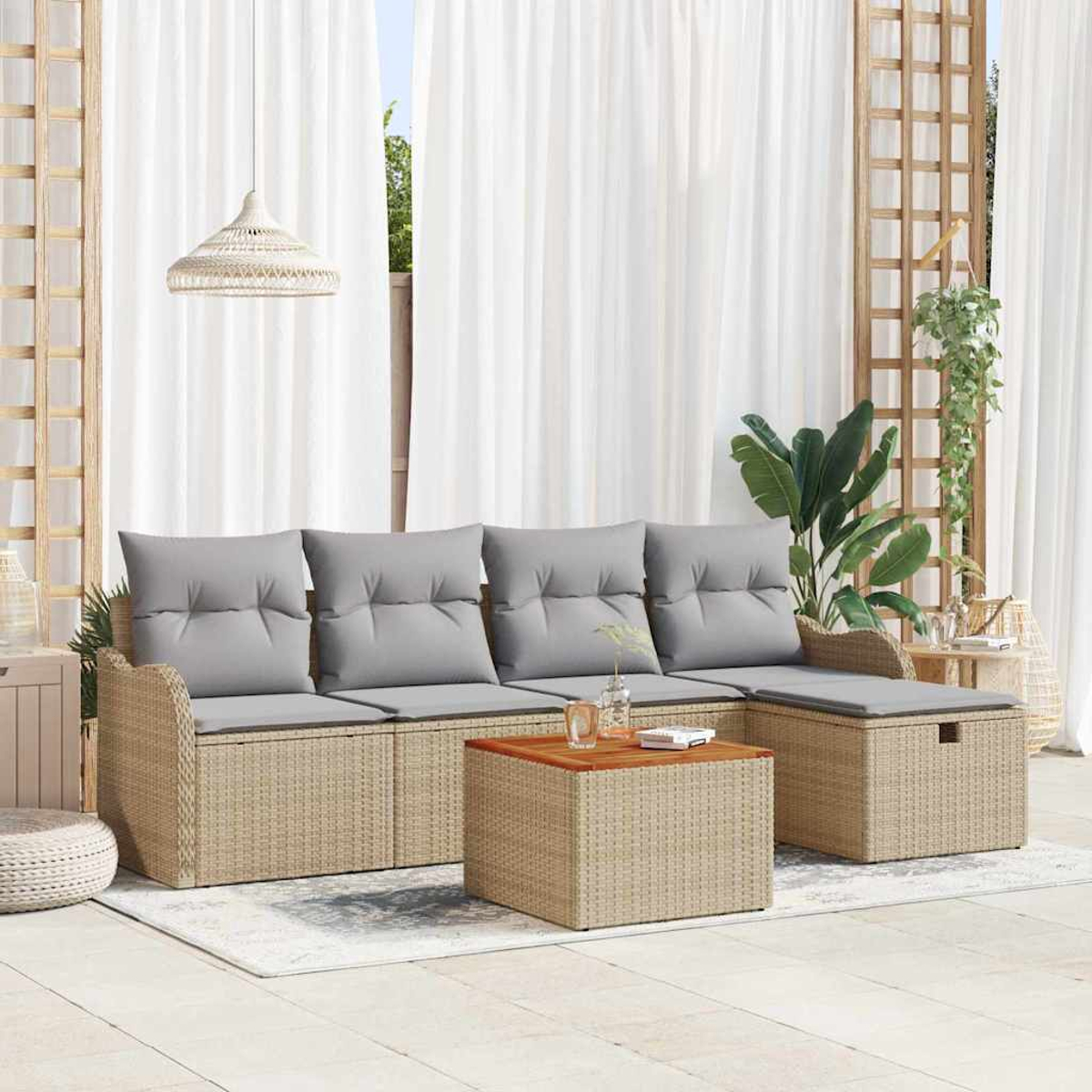 Terrassenset mit Rattan-Sofa, grauen Kissen und Holztisch. Weiße Vorhänge und Pflanzen schaffen eine entspannte Atmosphäre.