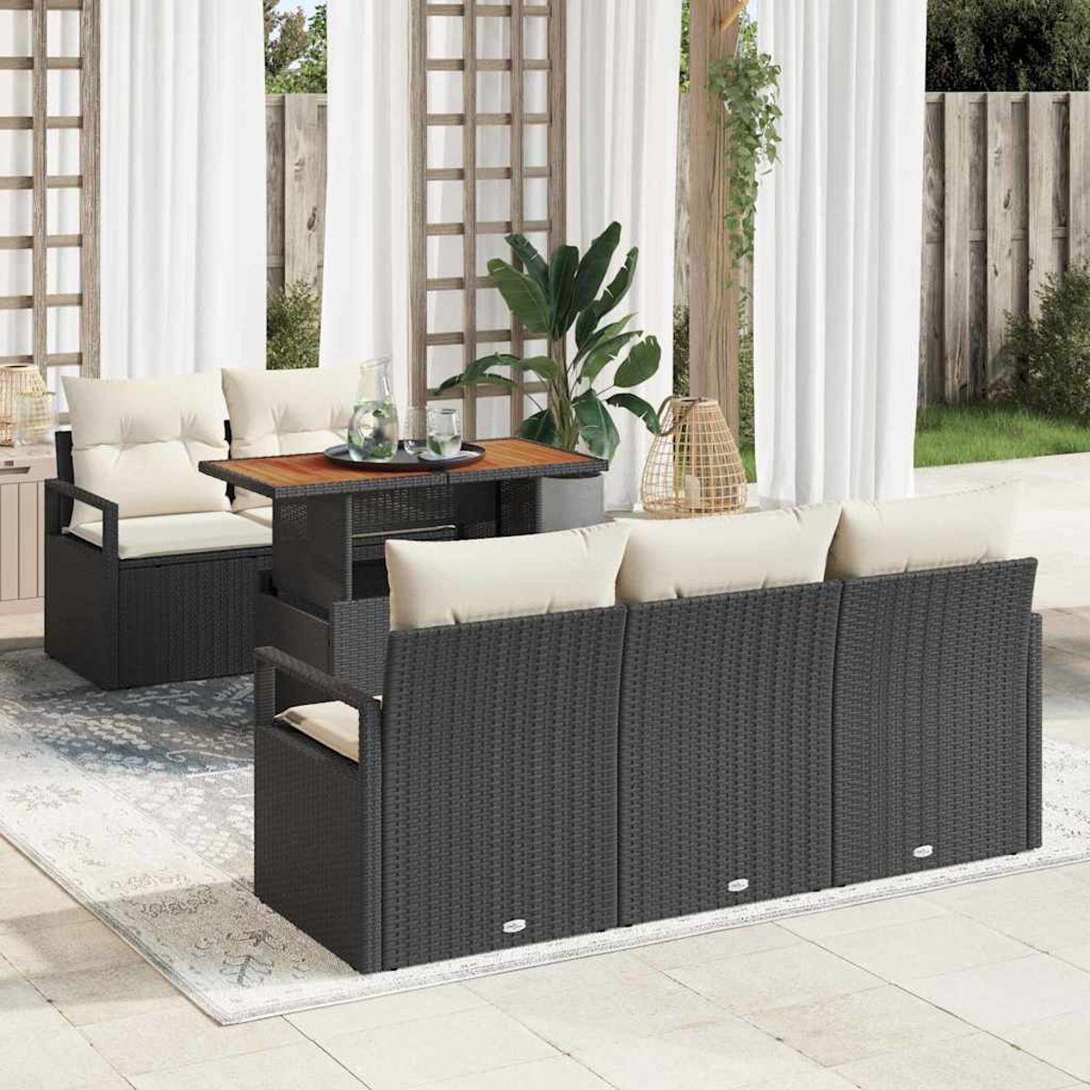 Juego de patio al aire libre con muebles de mimbre negro, cojines crema y una mesa de madera. Cortinas blancas y plantas crean un ambiente relajado.