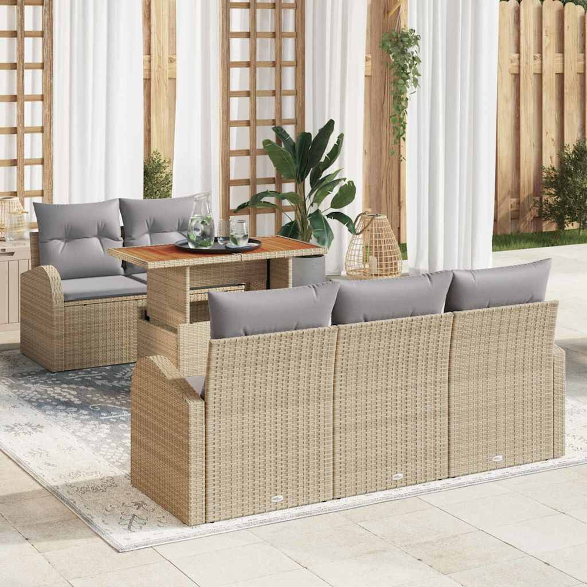 Terrassenmöbel. Beige Korbmöbel mit grauen Kissen, einem kleinen Tisch und weißen Vorhängen im Hintergrund.