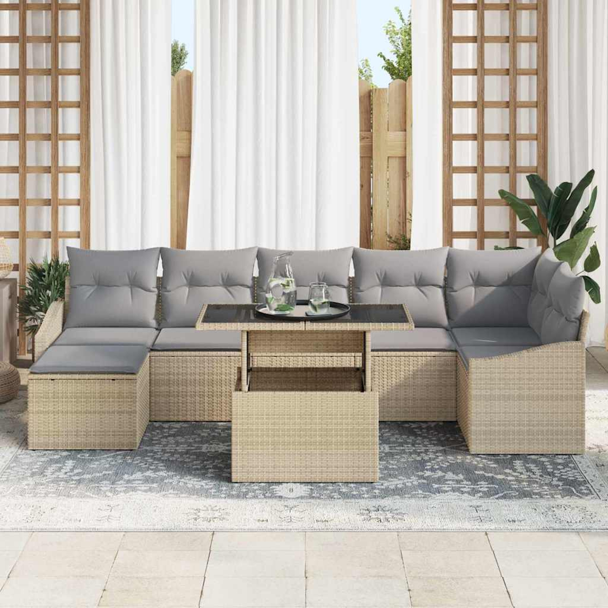 Gartenmöbel mit grauen Kissen und einem Tisch mit Glasplatte. Weiße Vorhänge und eine Pflanze im Hintergrund, auf einer Terrasse.