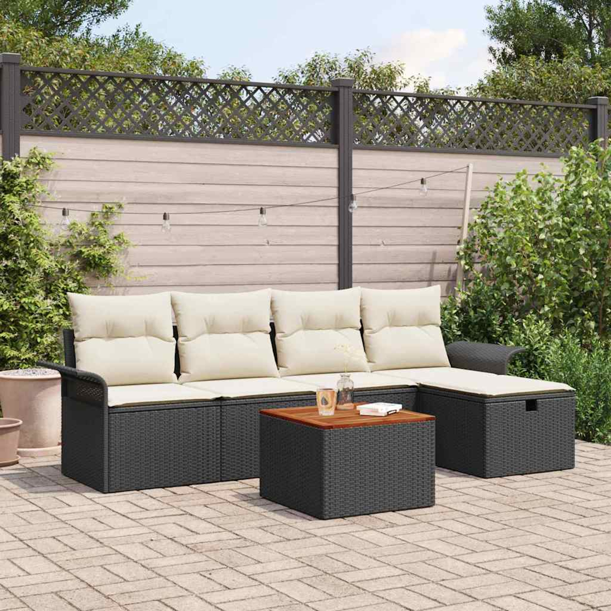 Outdoor-Terrassenset mit schwarzem Korbgewebe, beigen Kissen und einem hölzernen Couchtisch. Ein Zaun und Grün im Hintergrund.