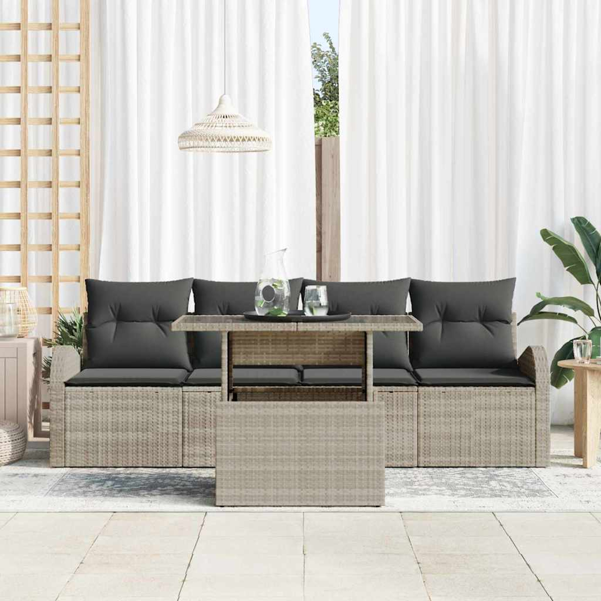 Garten-Sitzgruppe mit grauen Kissen, einem Tisch mit Getränken und weißen Vorhängen im Hintergrund.
