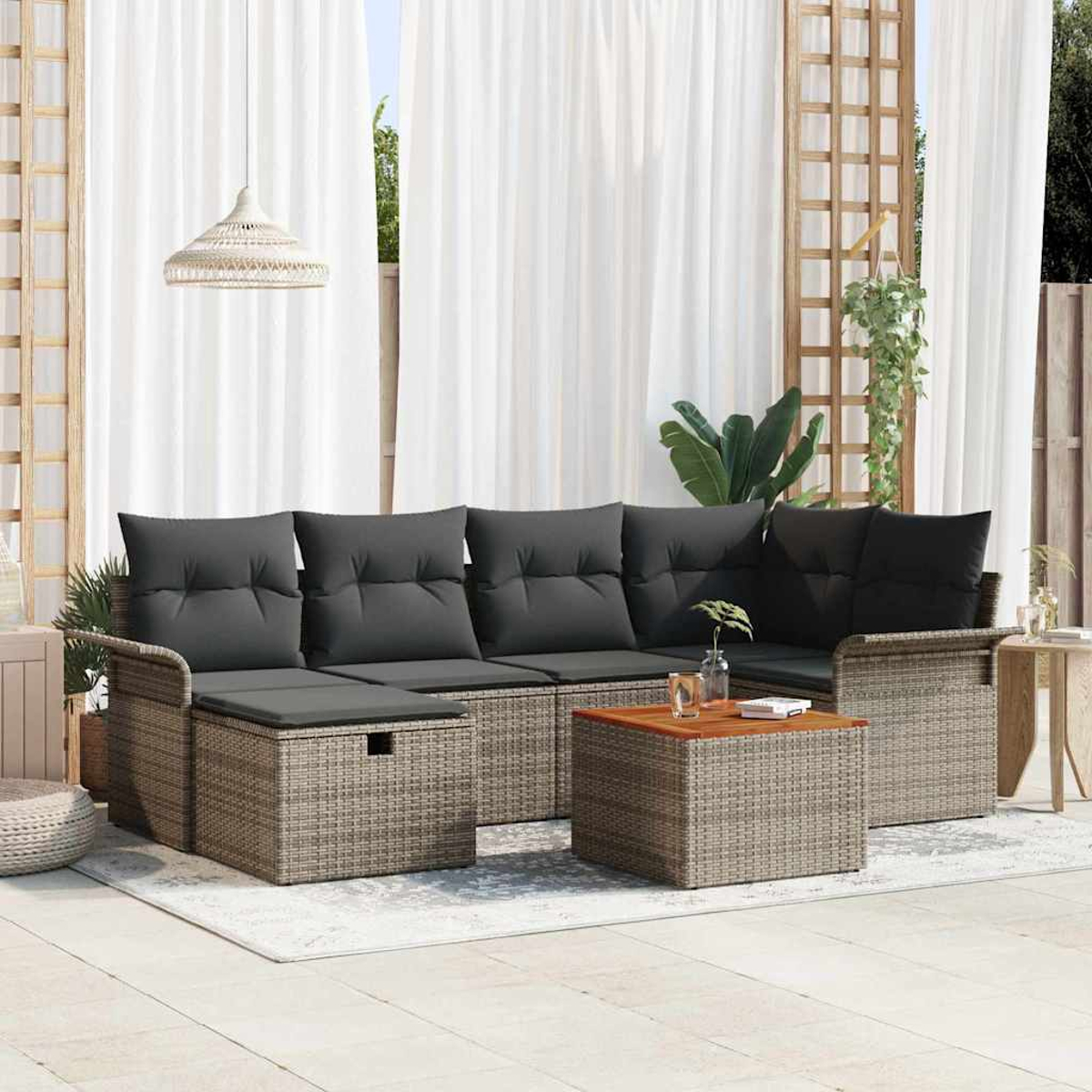 Garten-Sitzgruppe mit grauen Kissen und Rattangestellen, Couchtisch, weißen Vorhängen und einer Hängelampe.