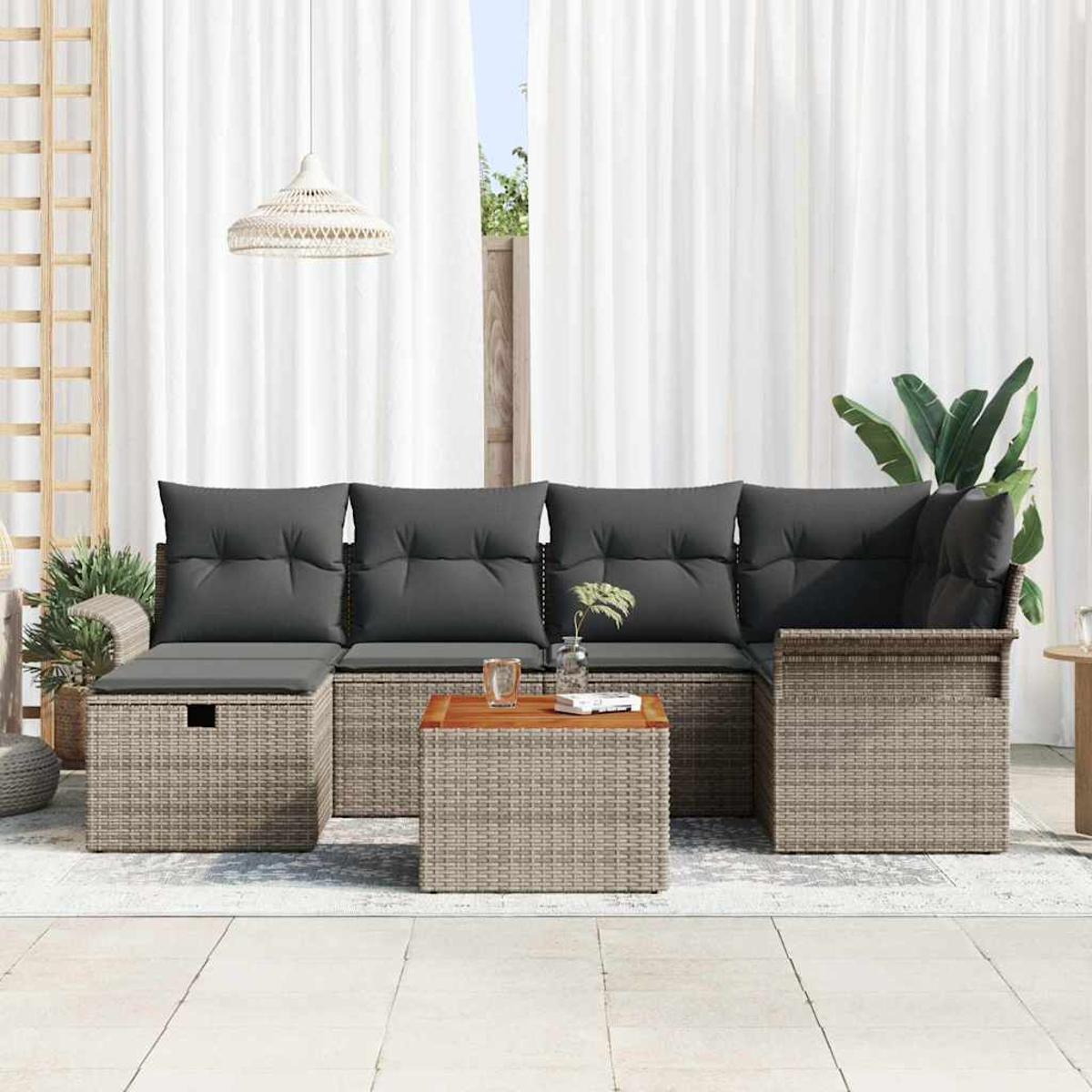 Gartenmöbel-Set mit grauen Kissen, einem kleinen Holztisch und weißen Vorhängen im Hintergrund.