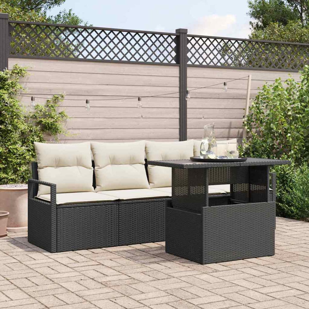 Garten-Terrassenset mit dunklem Korbsessel und Tisch. Beige Kissen. Holzzaun im Hintergrund. Getränke auf dem Tisch.