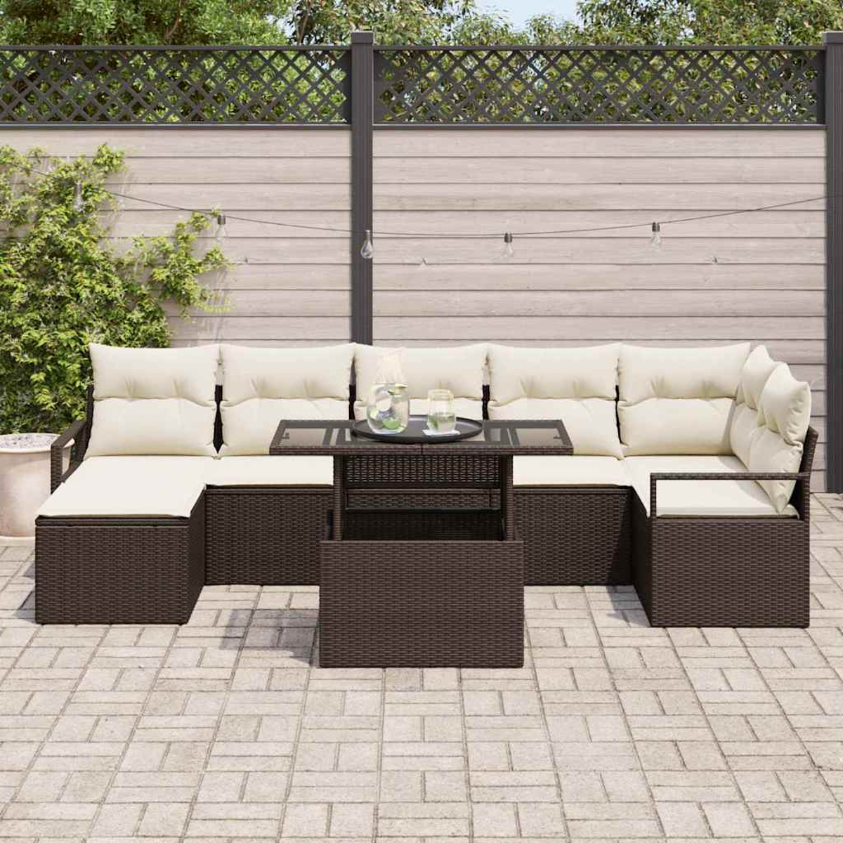 Ein Terrassenset mit braunem Weidenrahmen und cremefarbenen Kissen. Vorne steht ein Glastisch. Im Hintergrund ein Holzzaun und eine Pflanze.