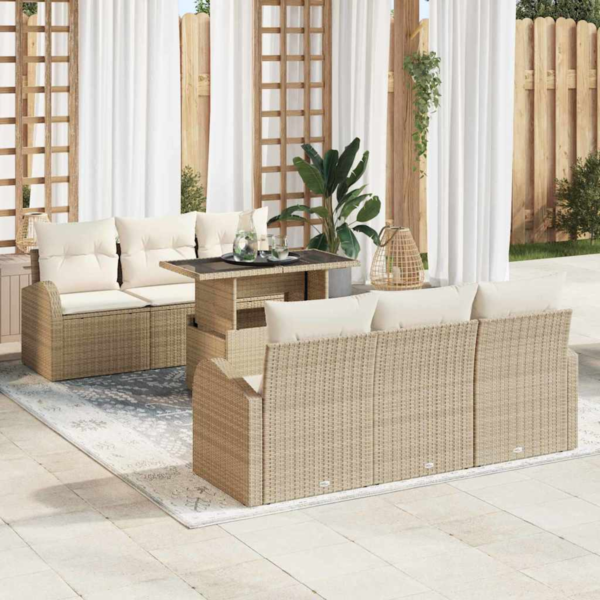 Juego de patio al aire libre con muebles de mimbre beige, cojines blancos, una mesa y una alfombra. El fondo incluye cortinas blancas y valla de madera.