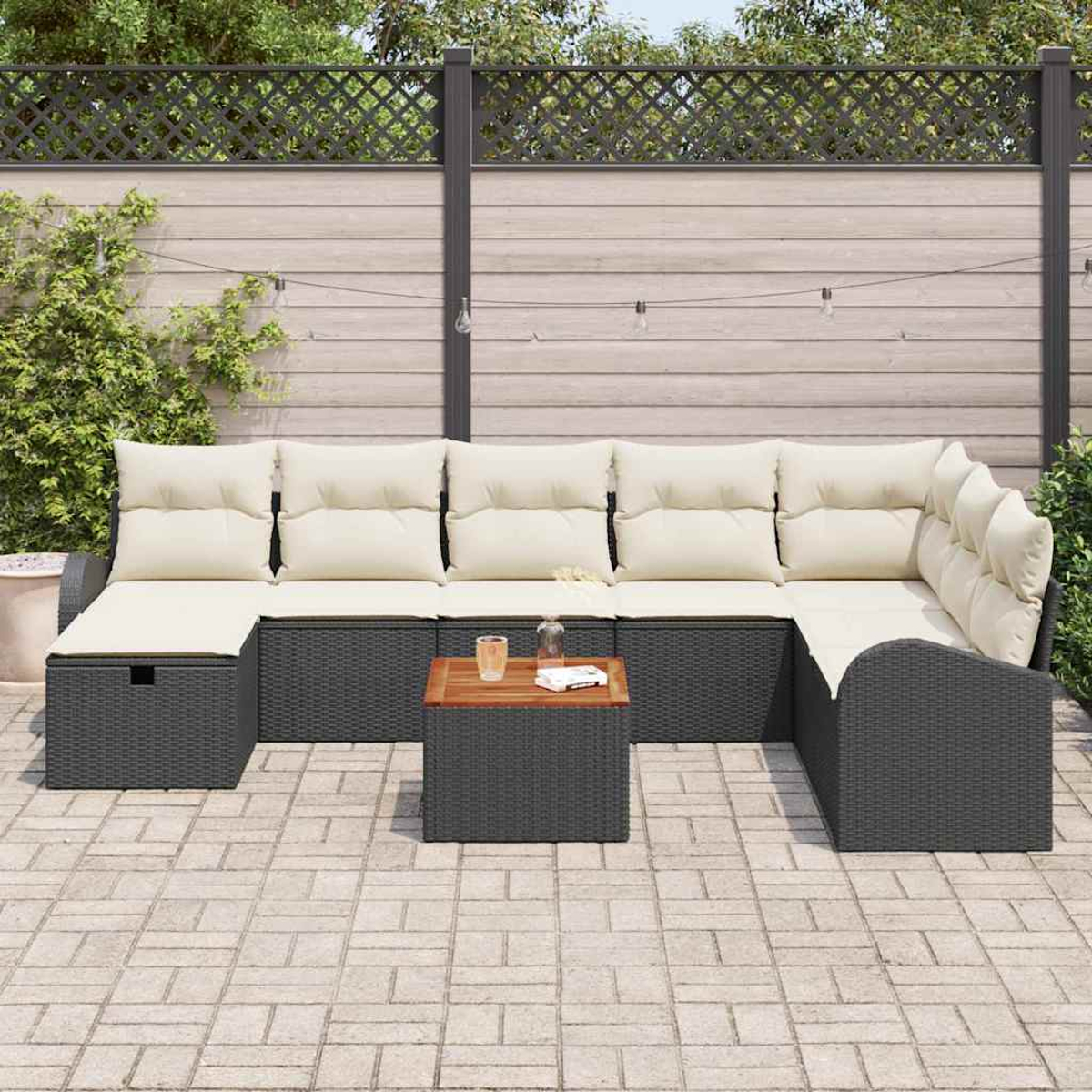 Outdoor-Ecksofa mit beigen Kissen. Holztisch mit Gläsern, Buch. Terrasse mit Ziegelfliesen, Zaun und Kletterpflanzen.
