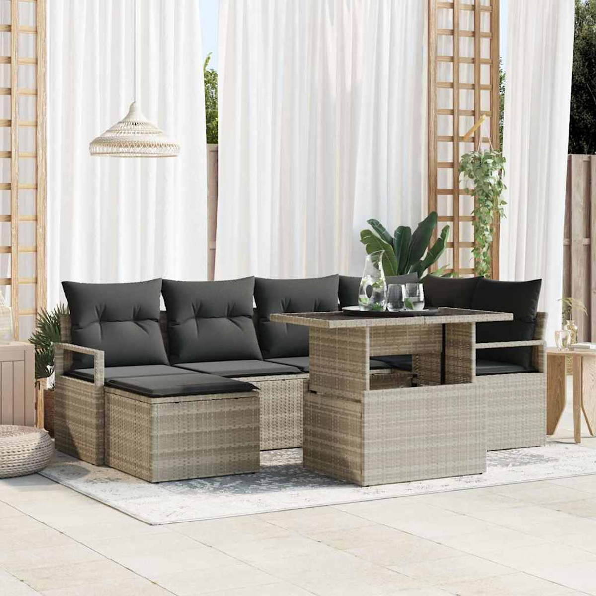 Rattan-Sofa-Set für den Außenbereich mit grauen Kissen, einem Tisch und weißen Vorhängen. Die Szene spielt sich auf einer Terrasse mit Pflanzen ab.