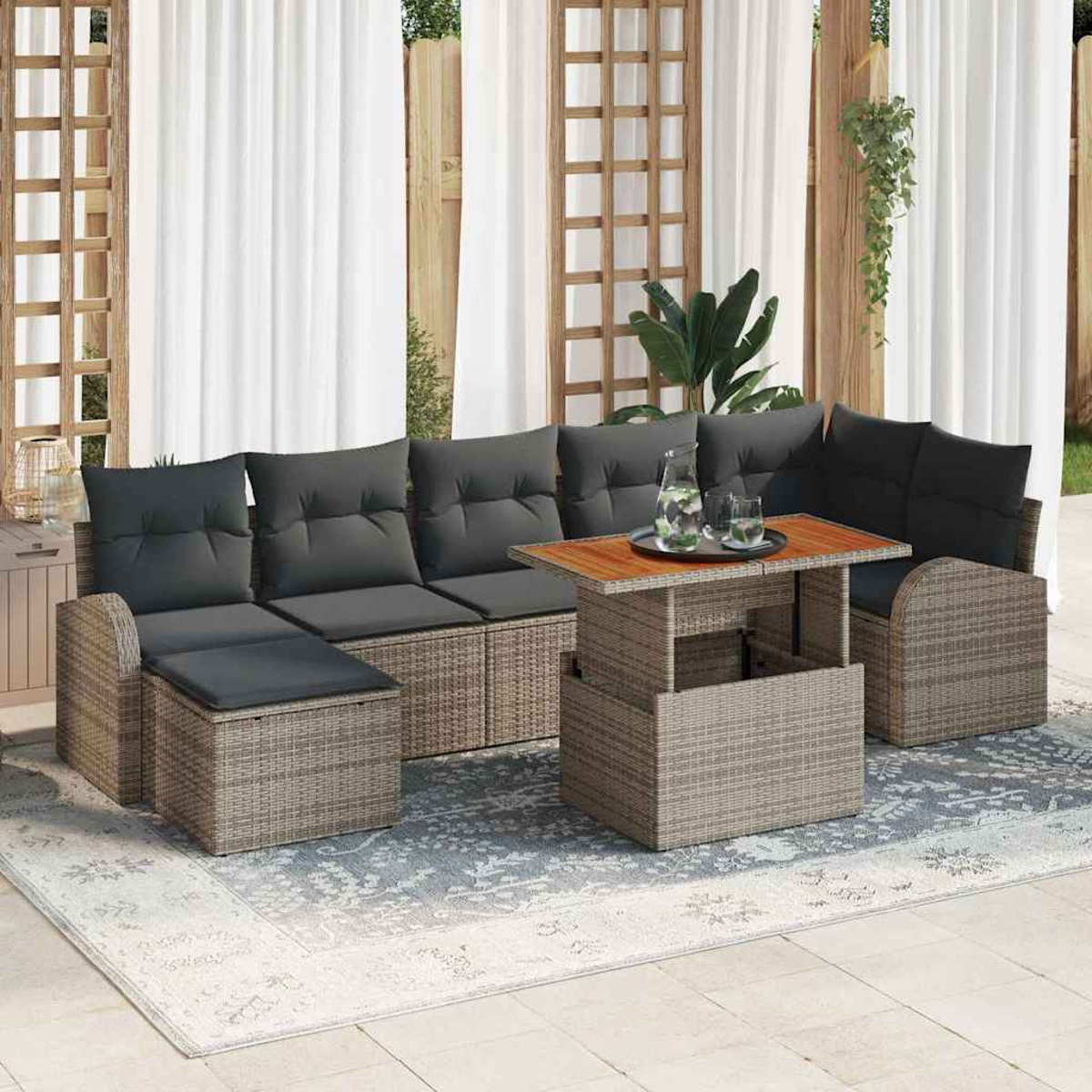 Outdoor-Korbmöbel-Set mit grauen Kissen, einem Holztisch mit Getränken und weißen Vorhängen im Hintergrund.