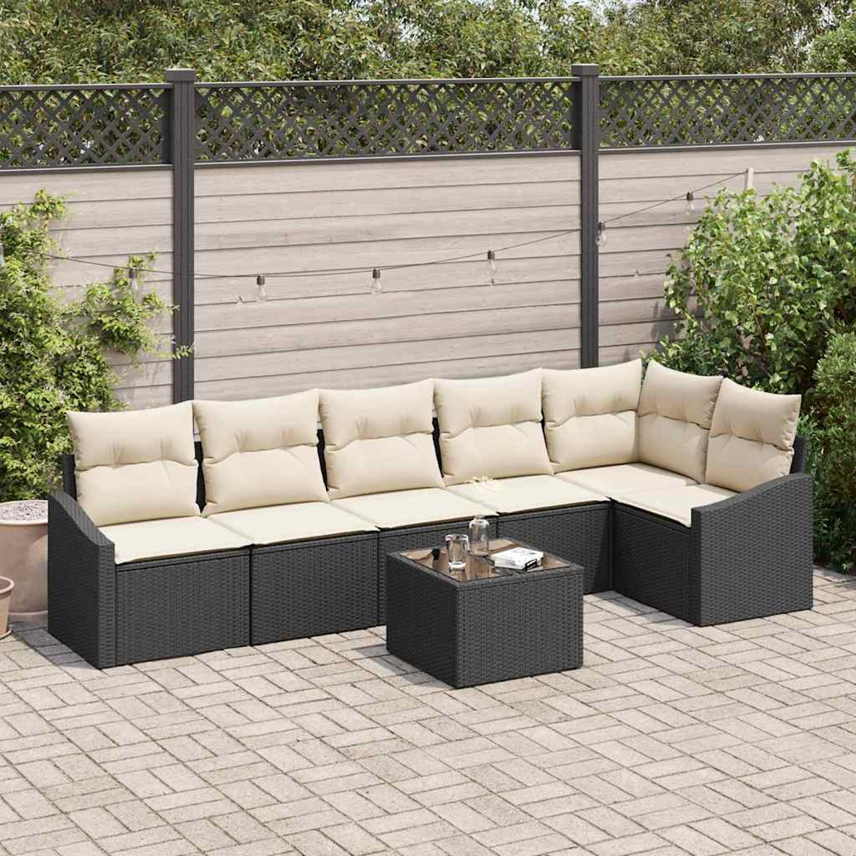Outdoor-Ecksofa mit beigefarbenen Kissen und einem kleinen Tisch auf einer Ziegelterrasse. Ein Zaun und Grünzeug sind im Hintergrund.