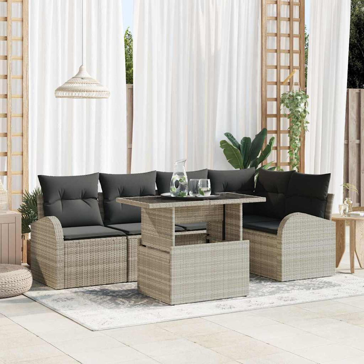Terrassenset im Freien mit grauen Kissen, Tisch mit Glas und weißen Vorhängen. Über der Szene hängt eine gewebte Leuchte.