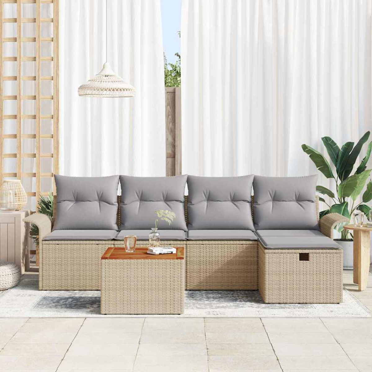 Rattansofa mit grauen Kissen und Holztisch. Weiße Vorhänge und eine Pflanze im Hintergrund.