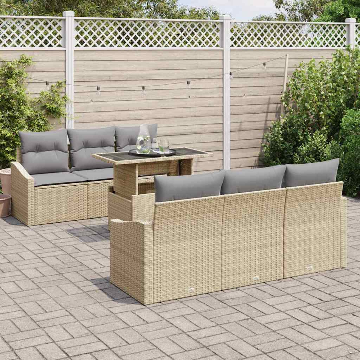 Gartenmöbel-Set. Beige Korbmöbel mit grauen Kissen und einem Tisch. Steinveranda mit Zaun im Hintergrund.