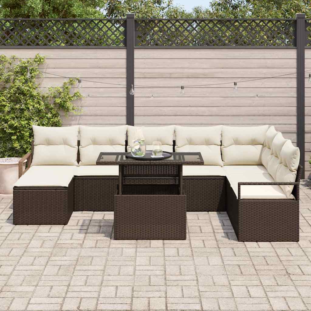 Outdoor-Ecksofa mit cremefarbenen Kissen und einem passenden Tisch auf einer Terrasse. Ein Zaun und Grün im Hintergrund.