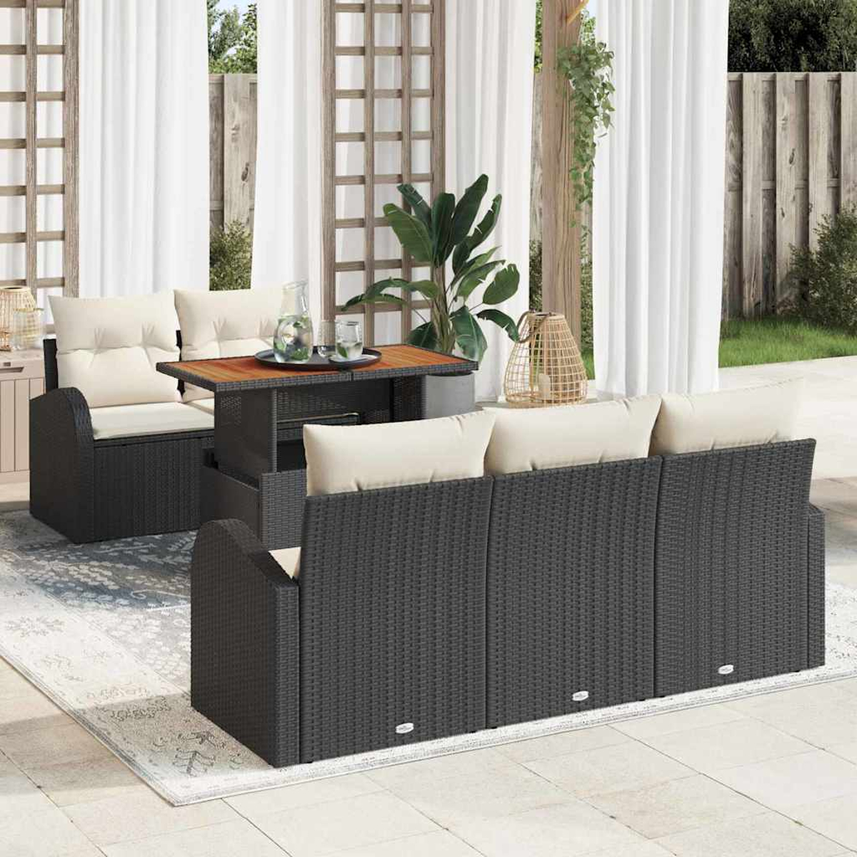 Terrassenset mit schwarzen Korbmöbeln, beigen Kissen, Holztisch und weißen Vorhängen im Hintergrund. Teppich auf dem Boden.