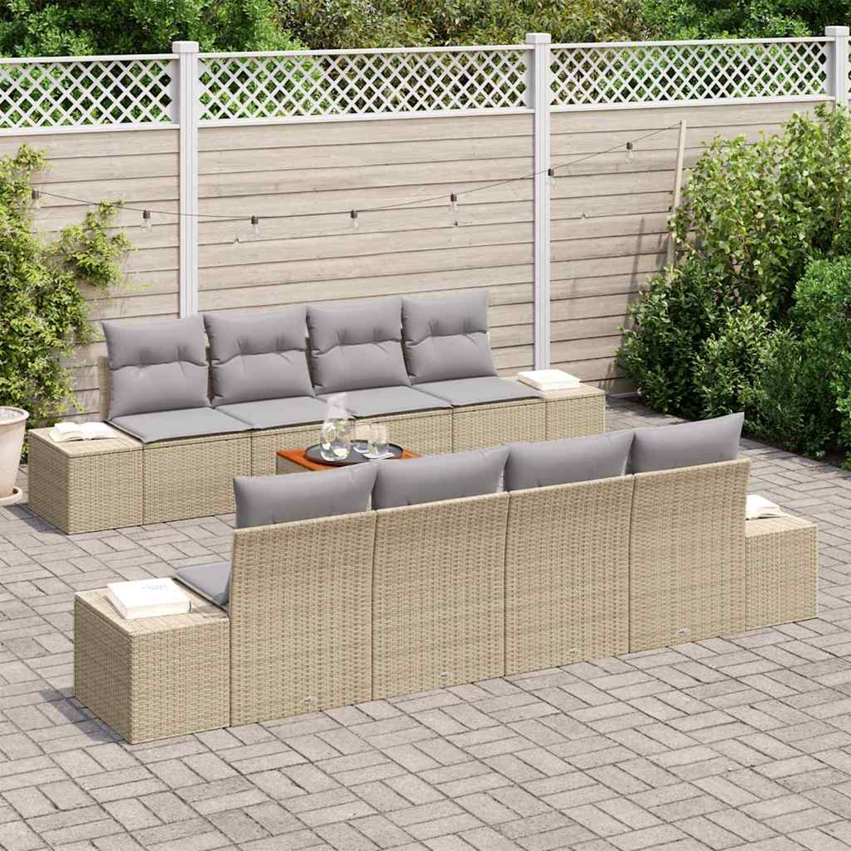 Outdoor-Sitzbereich mit Korbsitzgruppen und grauen Kissen. Ein Holztisch mit Getränken steht in der Mitte, im Hintergrund ein Zaun.