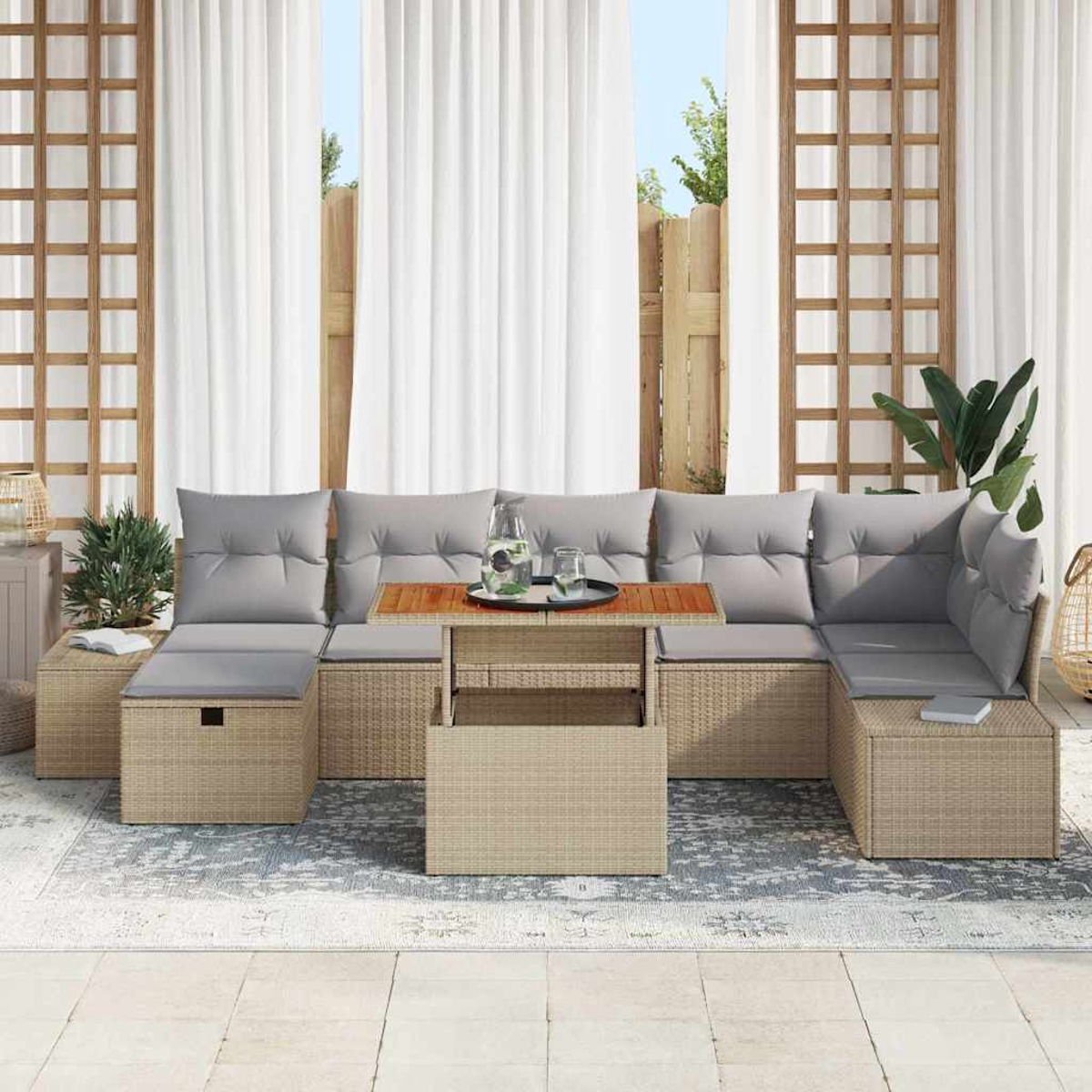 Ein Sitzensemble im Freien mit grauen Kissen und einem Holztisch. Weiße Vorhänge und ein Spalier sind im Hintergrund.