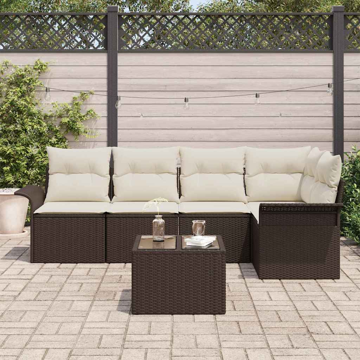 Garten-Sitzgruppe mit beigen Kissen, kleinem Tisch und Gartenhintergrund mit Zaun und Lichterketten.