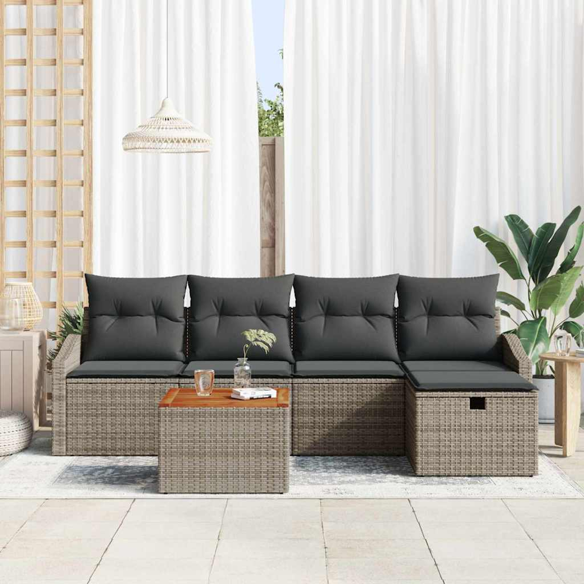 Ein Rattansofa mit grauen Kissen und einem Holztisch steht vor weißen Vorhängen. Eine Hängelampe und Pflanzen vervollständigen die Szene.
