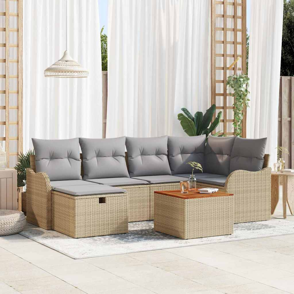 Outdoor-Korbsofa mit grauen Kissen und einem Holztisch. Weiße Vorhänge und eine Hängelampe im Hintergrund.