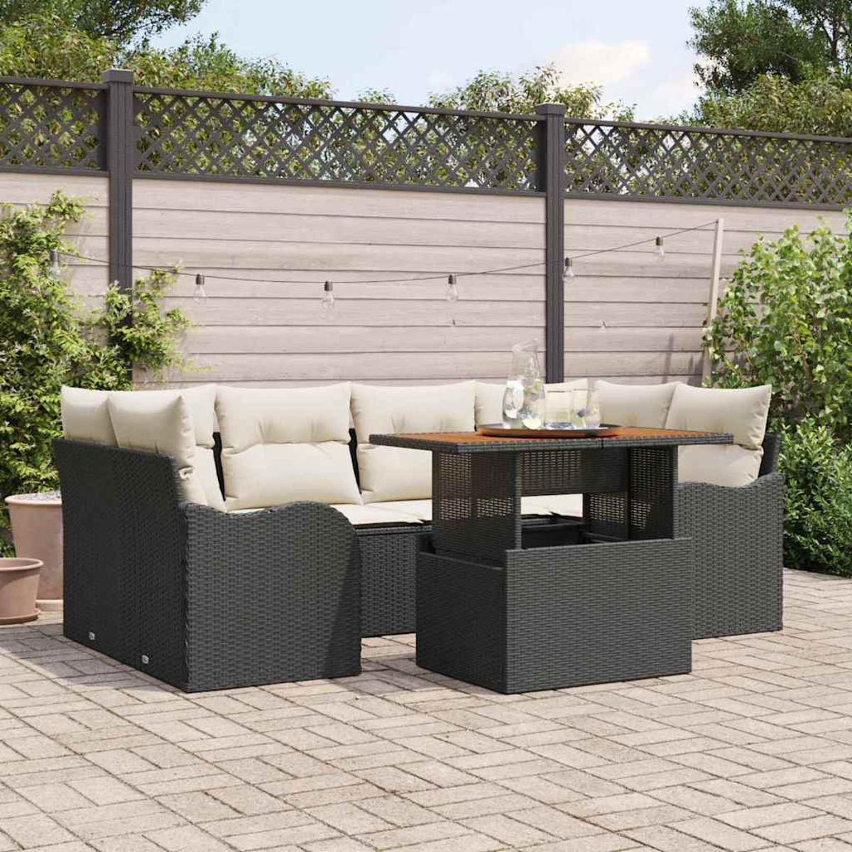 Gartenmöbel-Set. Dunkelgraues Korbmöbel-Set mit cremefarbenen Kissen und Holztischplatte. Terrasse im Garten.