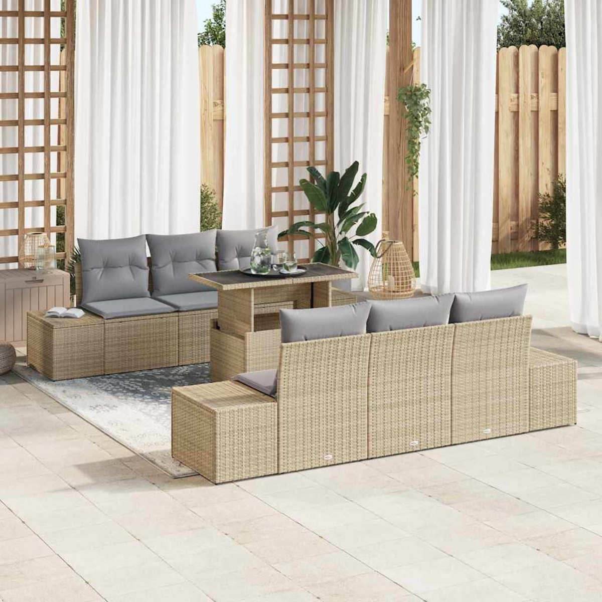 Outdoor-Sitzgruppe mit grauen Kissen und Tisch, vor weißen Vorhängen und Holzzaun, mit Pflanzen und einem Teppich.